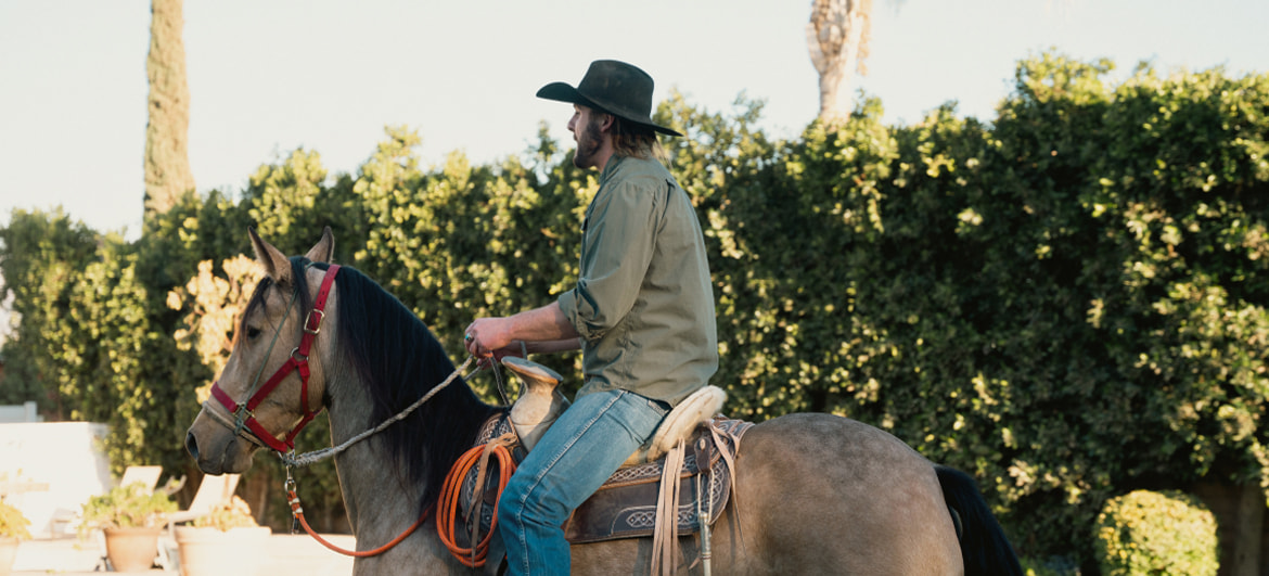 A participant engaging in equine therapy at Tranquility Recovery Center, riding a horse in a peaceful outdoor environment surrounded by greenery, promoting relaxation and personal growth.