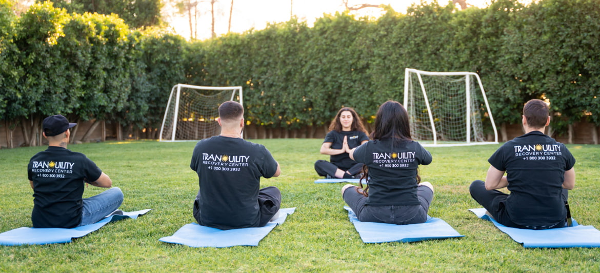 Group therapy session at Tranquility Recovery Center's outdoor area, where participants practice mindfulness and meditation in a peaceful environment.