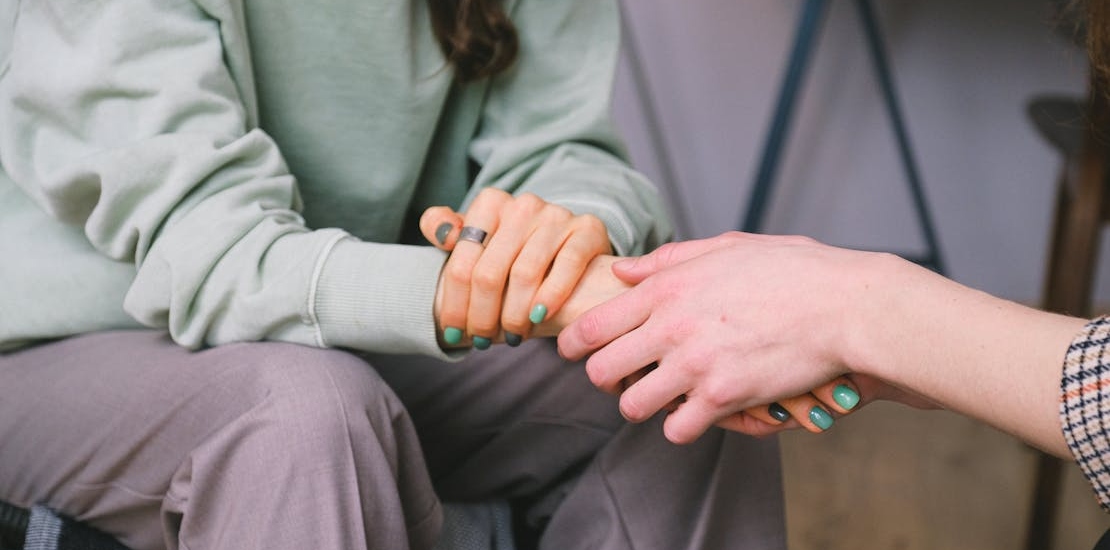 Two women holding hands in a psychotherapy session talking about how May Is Mental Health Awareness Month