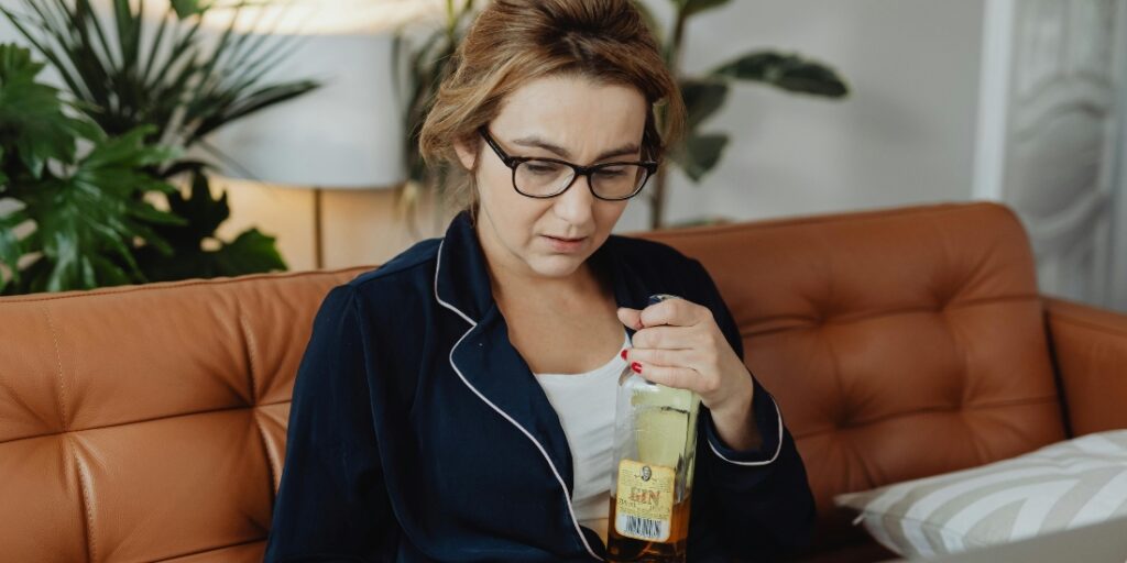 A person drinking alone at home, an example of how alcohol use can transition from social drinking to problematic behaviors in alcohol use disorder.