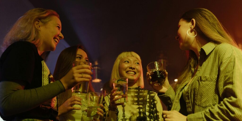 A group of friends at a club enjoying drinks together, highlighting the fine line between social drinking and the risk of alcoholism.