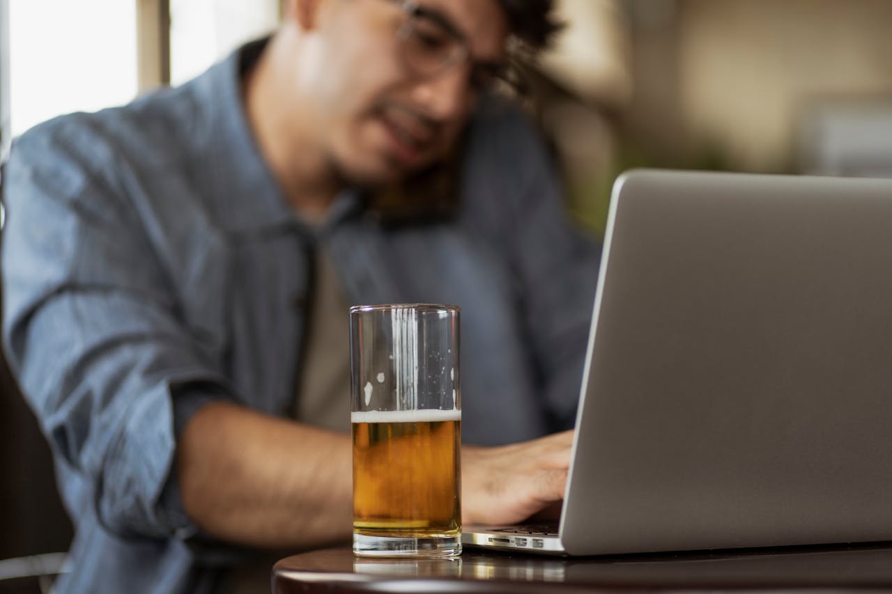 A man with a beer in the office as a symbol of alcoholism in the workplace