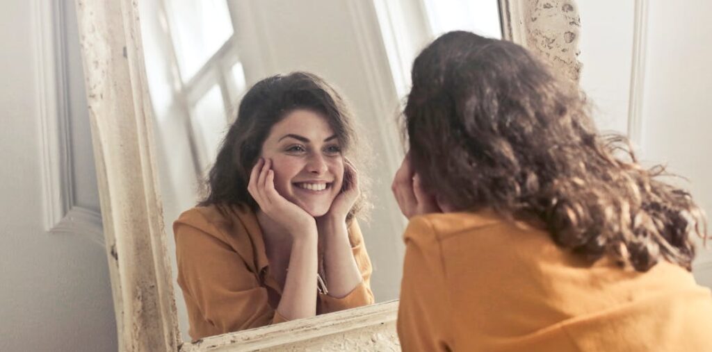 A girl looking at a mirror and smiling